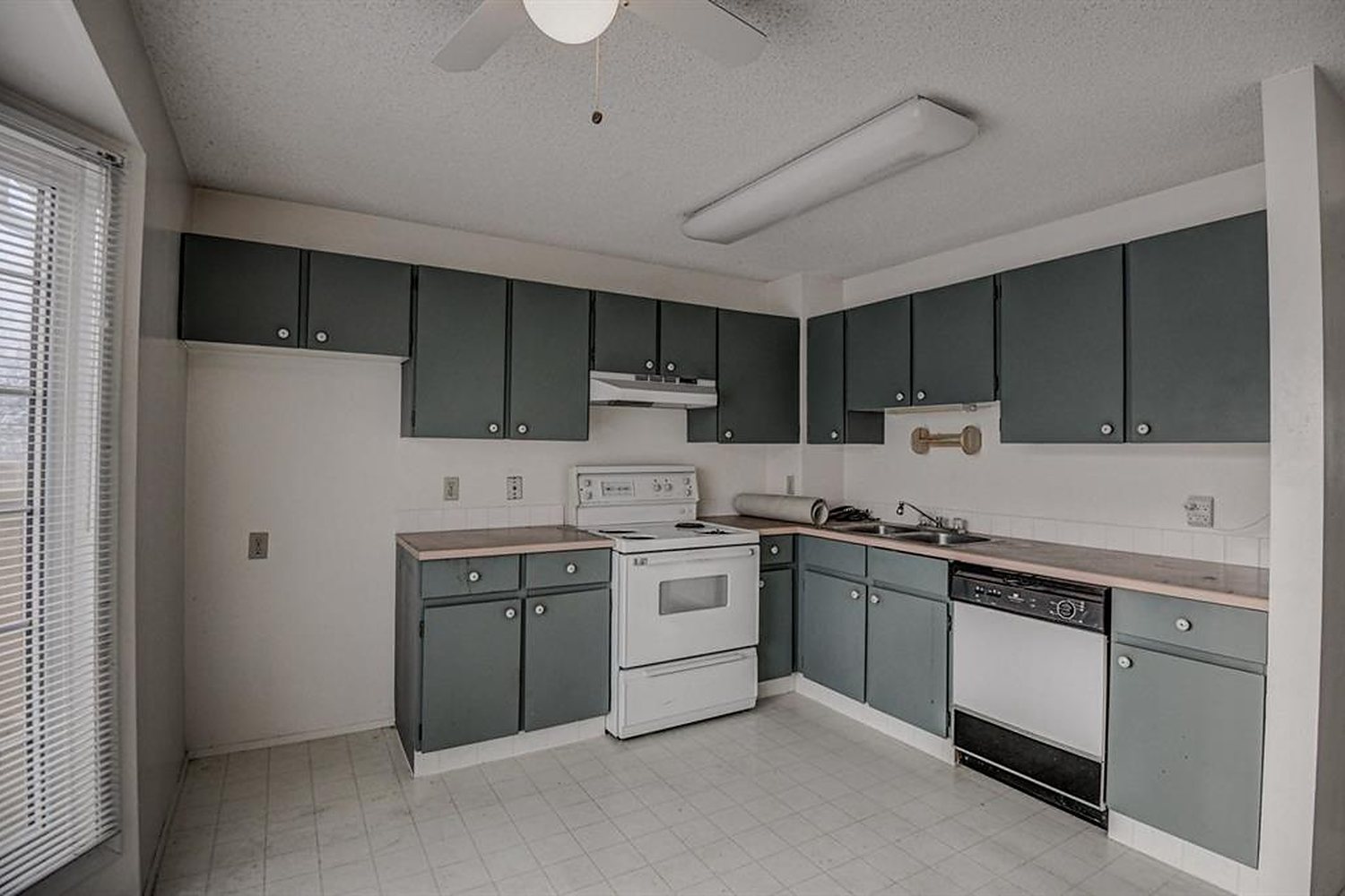 Original cabinets and laminate counters in a Calgary kitchen, photographed before renovation
