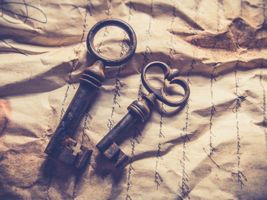 Two old iron keys lying on a crumpled sheet of handwritten paper