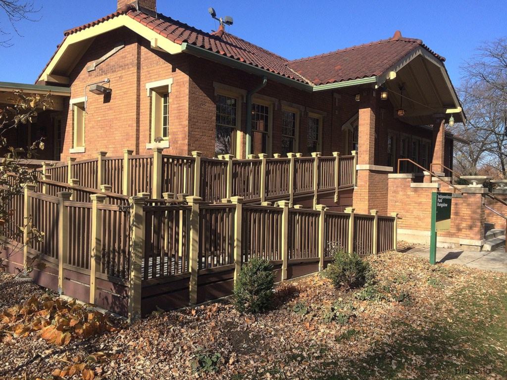 A red-brick bungalow with a tiled roof and a long wooden wheelchair ramp running across the front