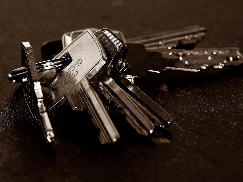 A bunch of house keys on a ring lying on a dark table